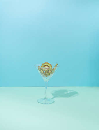 Modern conceptual setting of still life. Dried fruit in a cocktail glass. Two shades of blue in the background and green kiwi.の写真素材