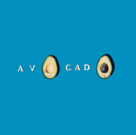 Avocado cut in half. Healthy food. The word of this magical fruit is written in letters. Blue...