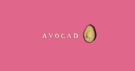 Avocado cut in half. Healthy food. The word of this magical fruit is written in letters. Pink...
