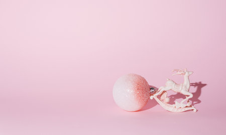 New Year's decorations on a pastel pink background. Reindeer and a big ball of white and pink color, sparkling. Conceptual setting.の写真素材
