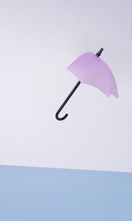 Broken purple umbrella in the wind. Two-tone background in shades of blue. Minimalism.の写真素材