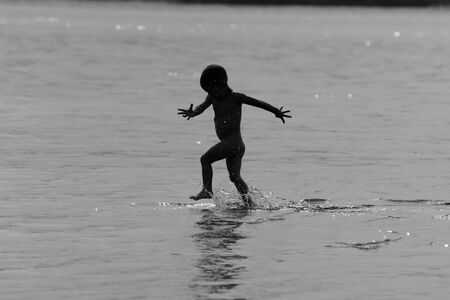 boy runs along the river and enjoys sprayの写真素材