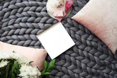 White paper sheet on the gray knitted blanket from merino woolの写真素材