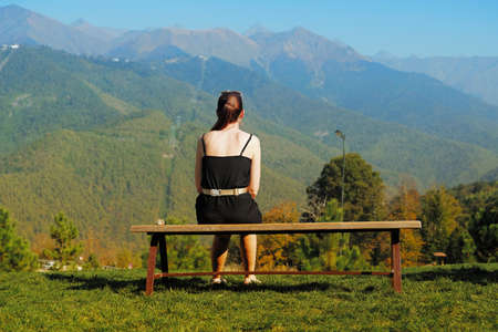 A woman sits on a bench while relaxing during her vacation in the mountains of Sochi, Russia.の写真素材