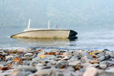 Beautiful landscape of the lake shore with a stone shore and an old boatの写真素材