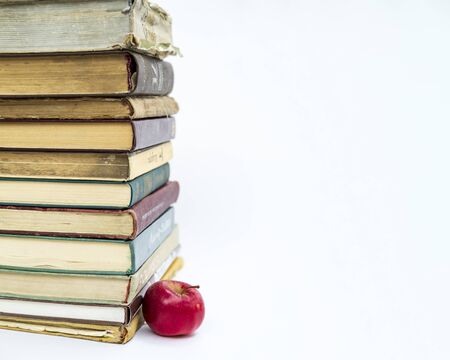 a stack of old books. Nearby lies a red apple. The concept of an idea came like a Newtons apple. On white background.の写真素材