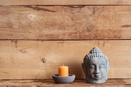 old cracked wooden planks background and stone buddha head with candle, free spaceの写真素材