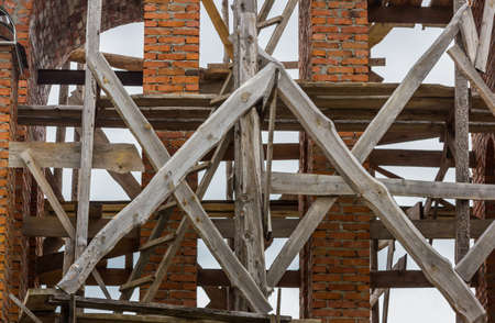 construction of a bell tower and a church. Brick wall. Wooden scaffoldingの写真素材