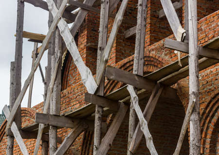 construction of a bell tower and a church. Brick wall. Wooden scaffoldingの写真素材