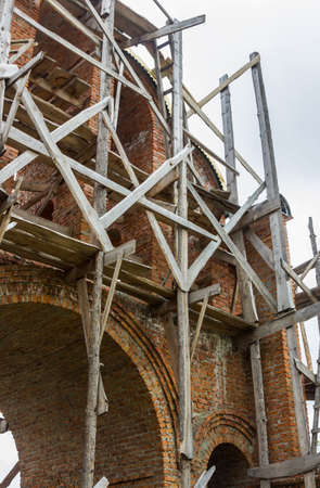 construction of a bell tower and a church. Brick wall. Wooden scaffoldingの写真素材
