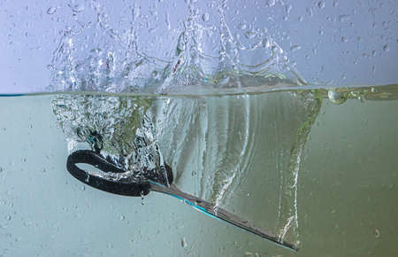 scissors fall into the water. sprays, drops and bubblesの写真素材