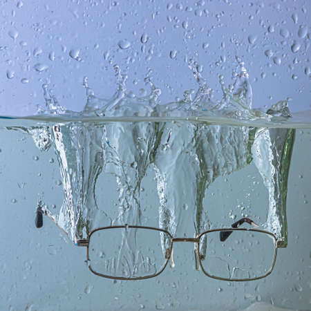 glasses fall into the water. sprays, drops and bubblesの写真素材