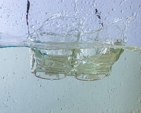 glasses fall into the water. sprays, drops and bubblesの写真素材