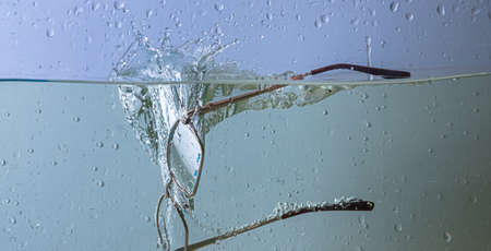 glasses fall into the water. sprays, drops and bubblesの写真素材