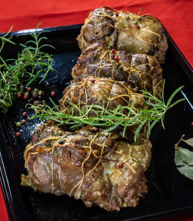 meat dish baked in the oven decorated with spices and rosemary on a dark backgroundの写真素材