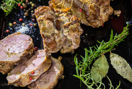 meat dish baked in the oven decorated with spices and rosemary on a dark backgroundの写真素材