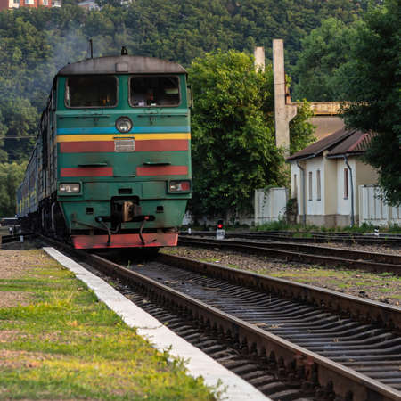 A diesel locomotive with wagons passes near the stationの写真素材