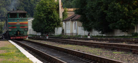 A diesel locomotive with wagons passes near the stationの写真素材