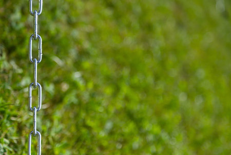 steel non-rusty chain on grass background, frame