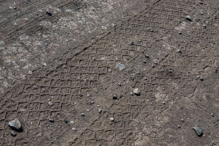 Close-up tire tracks truck on a dirt road in daylight.の写真素材