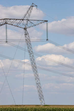 Overhead power line, power transmission line, support of high-voltage overhead power line, against the background of the sky with clouds.の写真素材