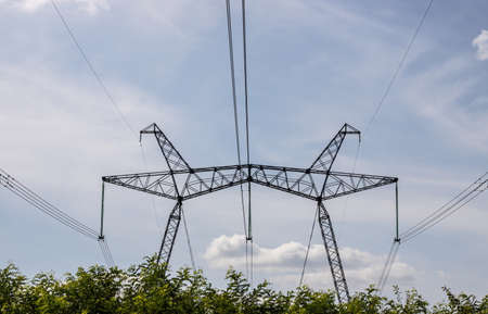 Overhead power line, power transmission line, support of high-voltage overhead power line, against the background of the sky with clouds.の写真素材