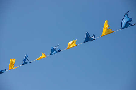 Yellow and blue triangular festival flags on sky background with white clouds. Outdoor Celebration Party. Festive moodの写真素材