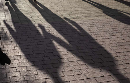 Shadows on pavement of two People walking under bright sunlight.の写真素材