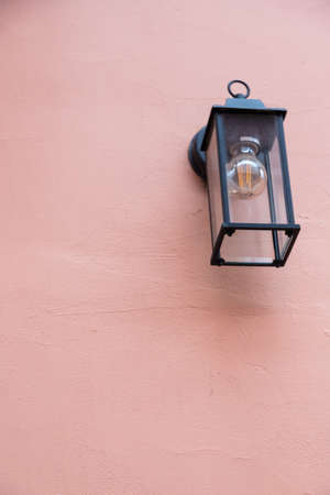 Old lantern with a white lamp. Wall color - Oriental Pink, Hue Red. Vintage lantern concept.の写真素材