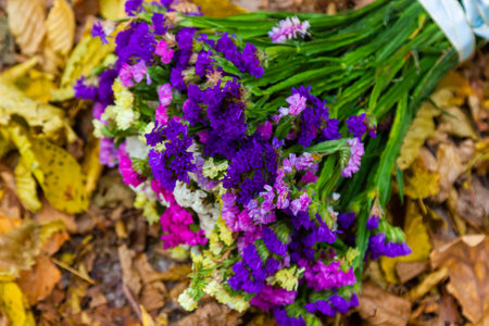 Flower bouquet in blue vase and apple on table on blue wooden wall background.の写真素材