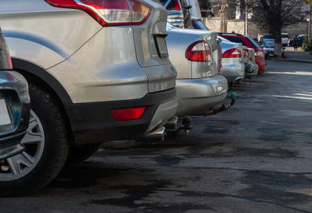 Closeup of rear, back side of golden car with other cars parking in outdoor parking area in sunny...
