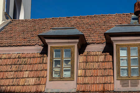 Ceramic tile roof with chimney and white wall, blue sky as background.の写真素材