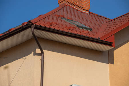 The roof of the house is made of red metal tiles, a beautiful large chimney.
