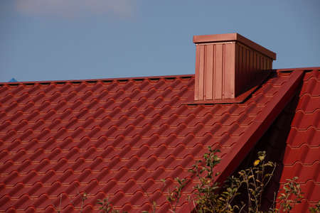The roof of the house is made of red metal tiles, a beautiful large chimney.