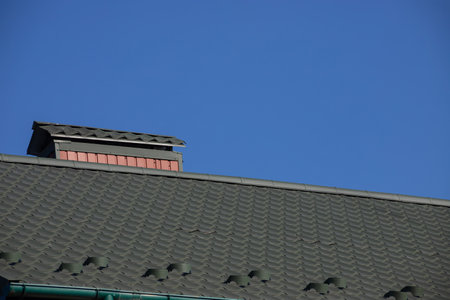 The roof of the house is made of red metal tiles, a beautiful large chimney.の写真素材