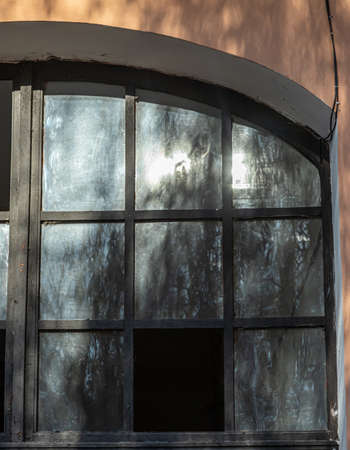 An old vintage wooden window with peeling paint oh frames needed to be repaired or replaced.