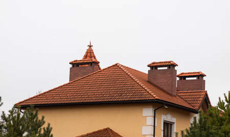 The roof of the house is made of red metal tiles, a beautiful large chimney.