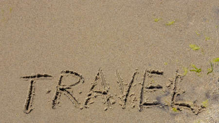 Travel concept - inscription in the sand. Sandy coast of the sea. motivation. ocean waves. The word travel is written on the sea beach. vacations on the shore.の写真素材