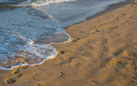 Footprints of a man on the yellow beach sand from walking barefoot by the sea with water that washes away the footprints. Contemplation of lifeの写真素材