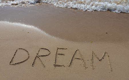 the inscription DREAM on the sand of the coastline.の写真素材