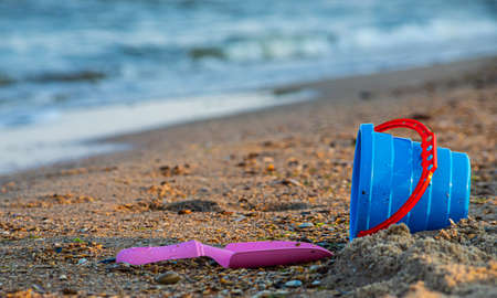 Children's toys on a sandy beach, blue sky and the sea in the background.の写真素材