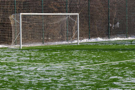 field for playing football in winter, artificial grass on cleared of snow in the distance gate and net.の写真素材