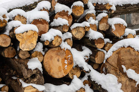snow-covered firewood. Stack of wood cut. Snow on the timber stack. Wooden log store under snow.の写真素材