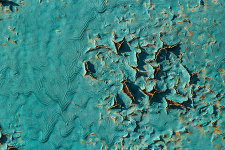 Blue peeling paint on the wall. Old concrete wall with cracked flaking paint. Weathered rough painted surface with patterns of cracks and peeling. High resolution texture for background and design.の写真素材
