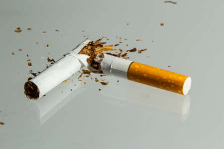 Broken cigarette fly in air on a light background. Conception of combat smoking.の写真素材