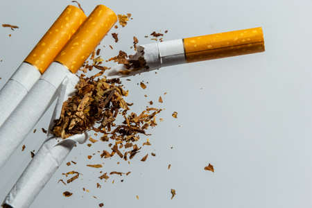 Broken cigarette fly in air on a light background. Conception of combat smoking.