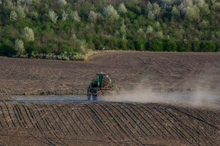 Tractor spraying pesticides on vegetable field with sprayer at spring.の写真素材