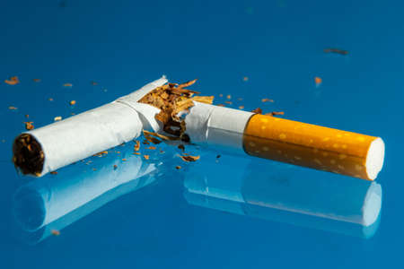 Broken cigarette on blue background. Stop smoking concept photography.の写真素材