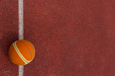 Orange ball for basketball lying on the sport court.Sport red court outdoor .Copy space.Top view.