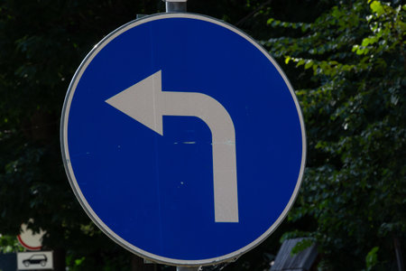 traffic signs, turn left signs with blurred background of trees and sparkling sunlight.の写真素材